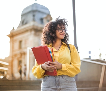 Uma estudante carregando seus cadernos e materiais de estudo